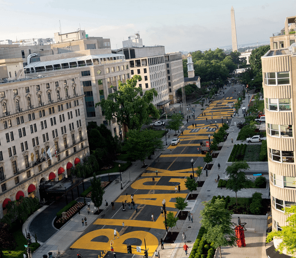 Racial equality and ethical consumerism. A mural of the words 'Black Lives Matter" painted in yellow on a road in Washington DC, 2 blocks from the White House, pointing to the Washington Monument. 