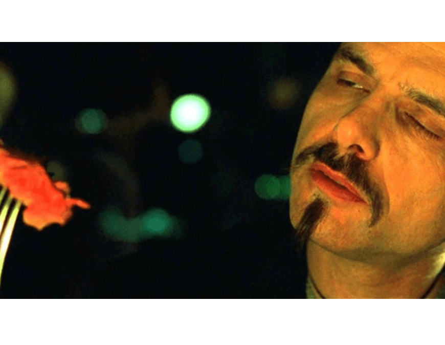 Cypher, a character from The Matrix, eats a piece of steak in a scene from the film. In the screenshot, Cypher holds a piece of rare steak on a fork as he considers it.