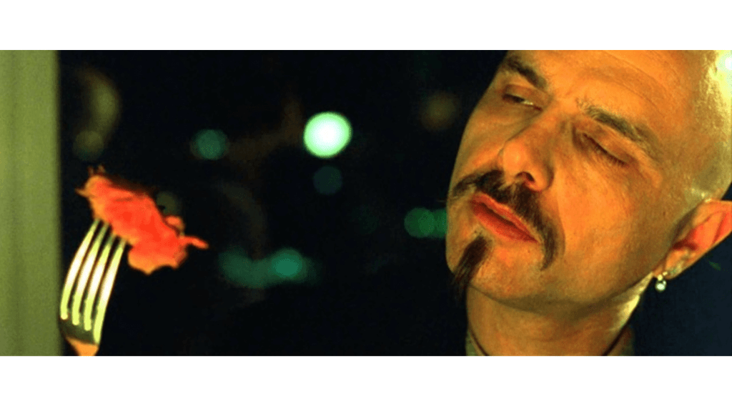Cypher, a character from The Matrix, eats a piece of steak in a scene from the film. In the screenshot, Cypher holds a piece of rare steak on a fork as he considers it.