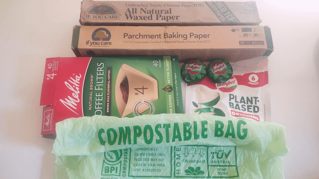 A photo of 6 certified compostable products: waxed paper and parchment paper from If You Care, coffee filters from Melita, vegan cheese from Babybel, and compostable food waste bag from BioBag. 