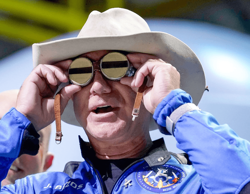 Jeff Bezos, CEO of Amazon.com, returns from a space flight wearing a blue suit and a cowboy hat. I the photo, Bezos is trying on goggles that belonged to aviator Amelia Earhart. (Amazon withdraws support for older Kindles)
